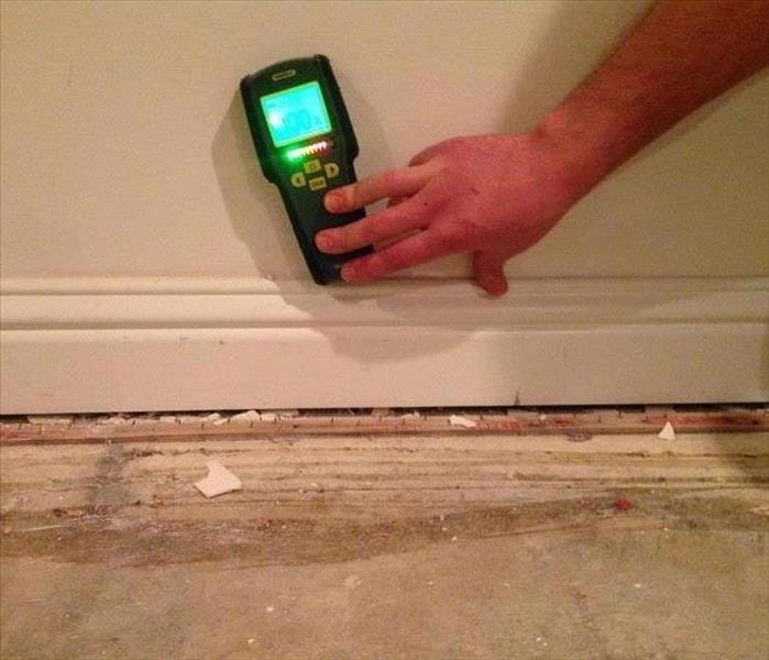This picture shows one of our technicians holding a moisture meter up to a wall reading whether it's wet or dry. 