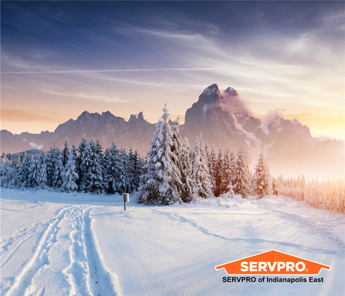 "Snow-covered landscape with pine trees and mountains in the background at sunset, with SERVPRO logo on right bottom corner